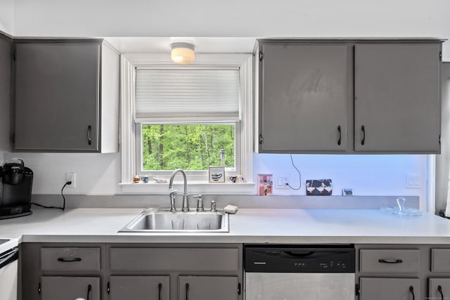 kitchen featuring dishwasher, gray cabinetry, a sink, and light countertops