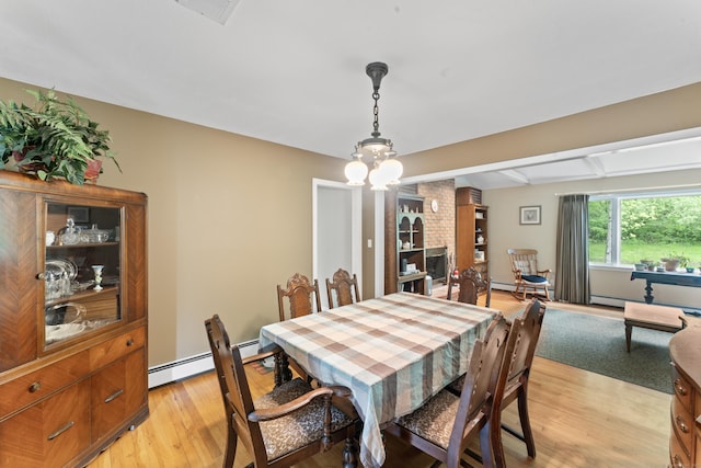dining area with a baseboard heating unit, light wood-type flooring, a baseboard radiator, and beamed ceiling