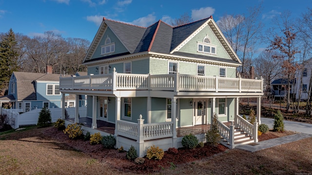 victorian house with covered porch, a balcony, and fence