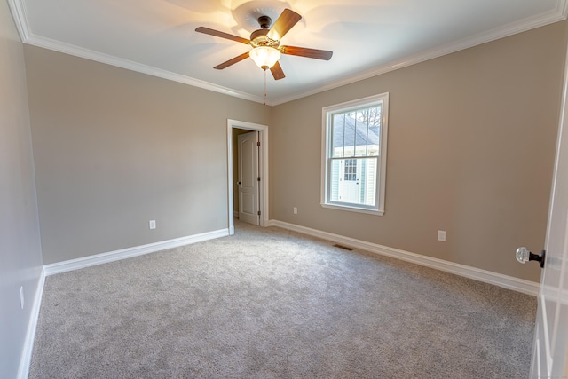 carpeted empty room featuring ornamental molding, ceiling fan, and baseboards