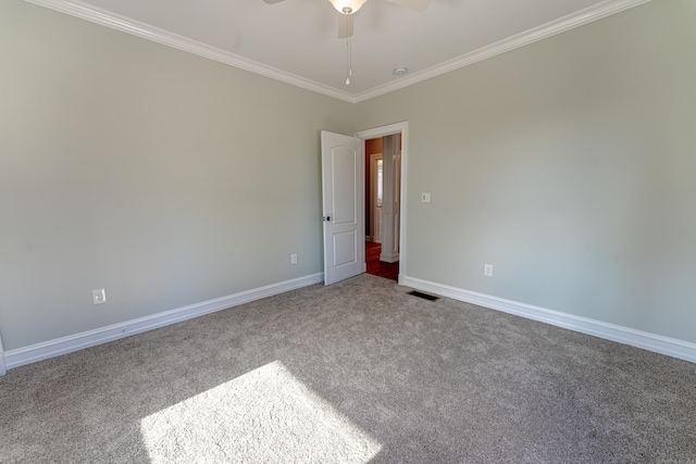 carpeted spare room featuring ornamental molding, ceiling fan, and baseboards