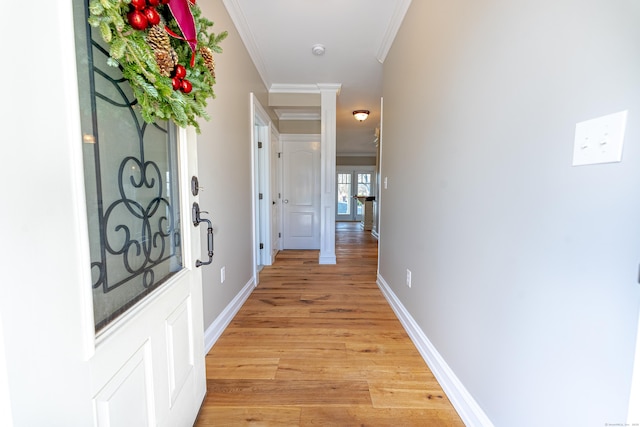 corridor featuring ornamental molding, light wood-style flooring, and baseboards