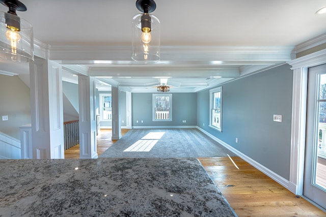 unfurnished dining area featuring ornate columns, crown molding, light wood finished floors, baseboards, and beam ceiling