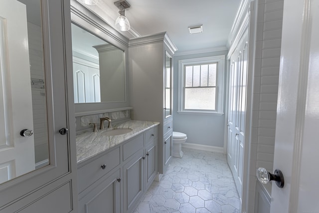 bathroom featuring ornamental molding, toilet, vanity, and baseboards