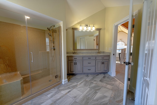 full bath featuring a stall shower, double vanity, vaulted ceiling, and baseboards