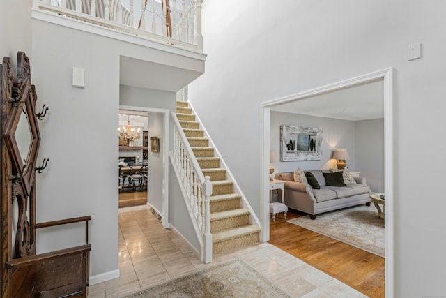 11 Thomas Rd, Westport, CT 06880 - stairway featuring a chandelier, tile patterned flooring, crown molding, a high ceiling, and baseboards