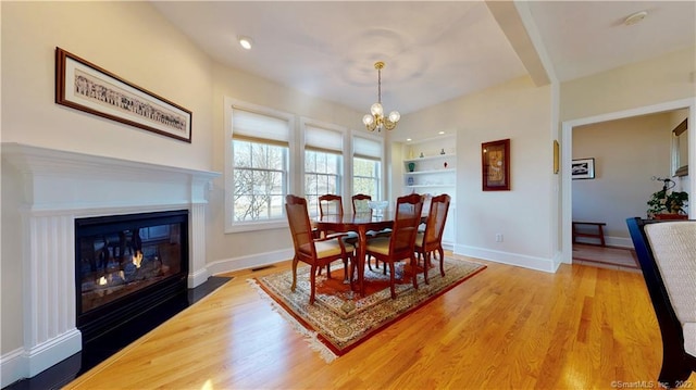 196 Jefferson St, Stratford, CT 06615 - dining area featuring built in features, a chandelier, light wood-type flooring, baseboards, and a fireplace with flush hearth