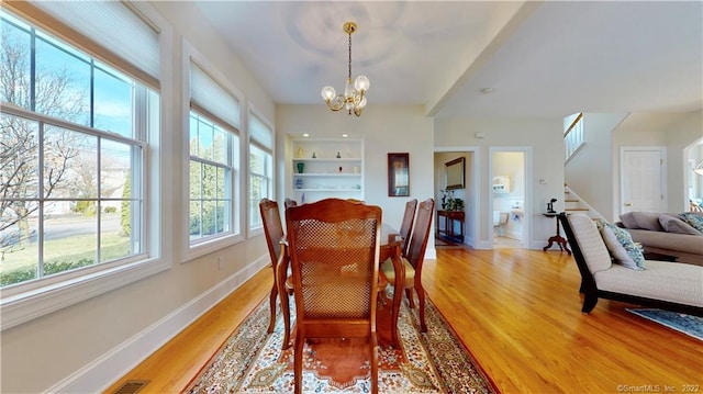 196 Jefferson St, Stratford, CT 06615 - dining area with light wood-style floors, a chandelier, stairs, baseboards, and built in shelves