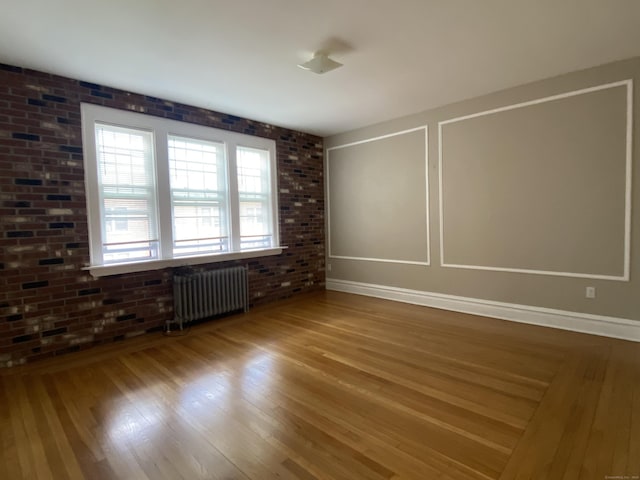 139 Fountain St Apt B9, New Haven, CT 06515 - spare room featuring radiator heating unit, wood finished floors, and brick wall