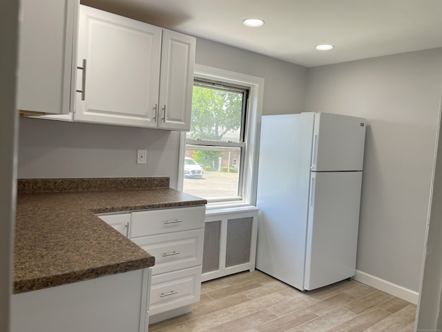kitchen with freestanding refrigerator, dark countertops, radiator heating unit, white cabinetry, and light wood-style floors