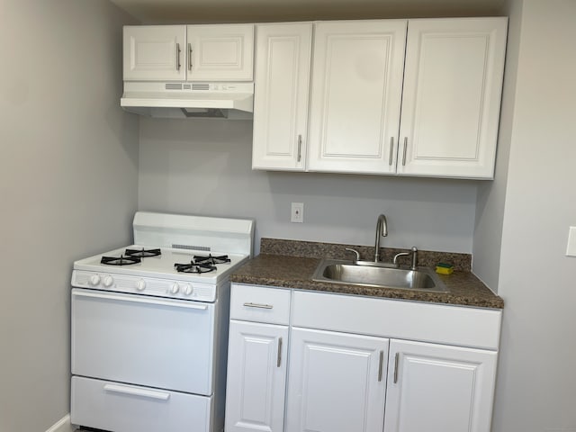 kitchen featuring under cabinet range hood, white range with gas stovetop, a sink, dark countertops, and white cabinets