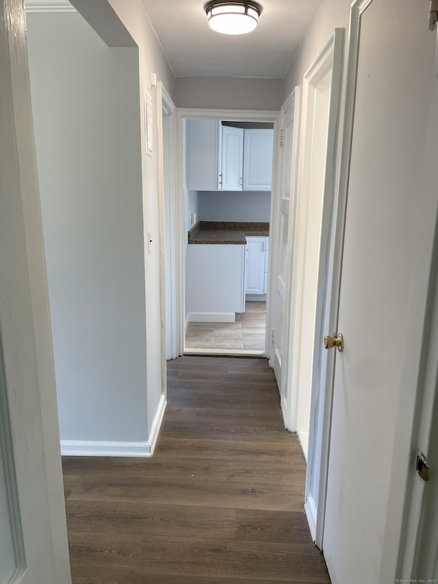 corridor featuring dark wood-style floors and baseboards