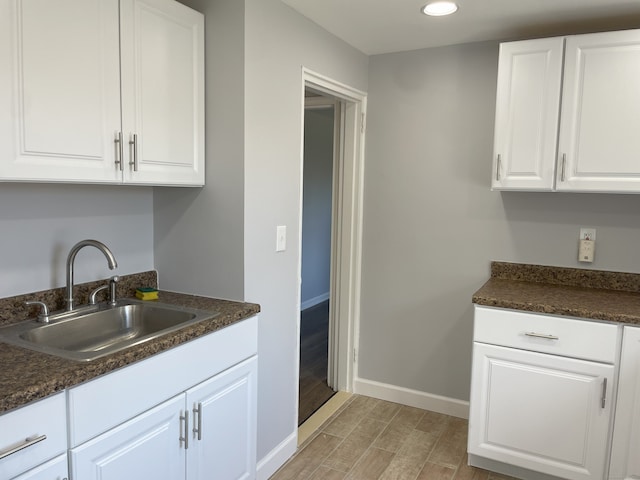 kitchen featuring a sink, baseboards, wood tiled floors, dark countertops, and recessed lighting