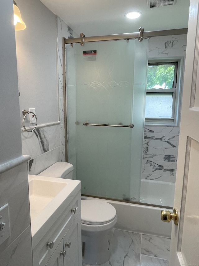 bathroom featuring marble look tiles, toilet, vanity, and enclosed tub / shower combo