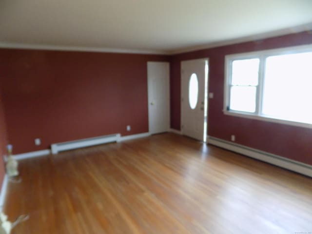 foyer entrance with baseboard heating, light wood-type flooring, and baseboards