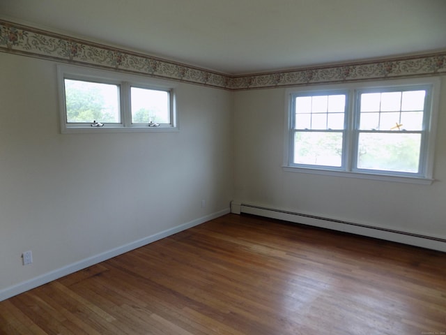 spare room with a baseboard radiator, wood finished floors, and baseboards