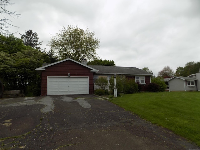 view of front of house featuring asphalt driveway, an attached garage, and a front yard