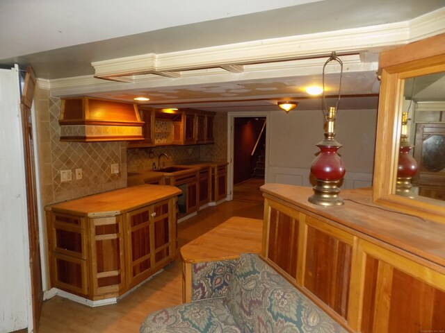 bar area with a sink, light wood-style floors, stairway, and backsplash