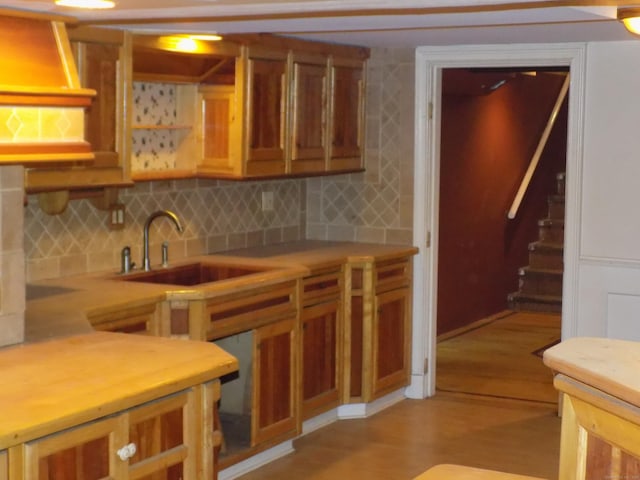 kitchen featuring a sink, open shelves, light wood-type flooring, light countertops, and decorative backsplash