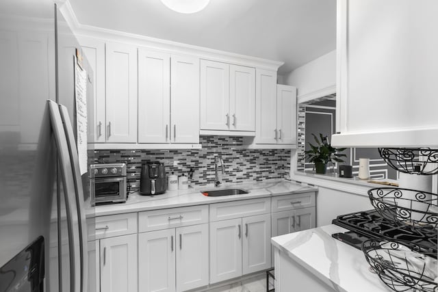2370 N Ave Unit 12G, Bridgeport, CT 06604 - kitchen featuring freestanding refrigerator, a sink, decorative backsplash, and white cabinetry