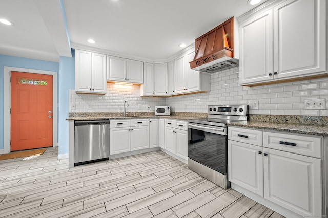 29 E Cliff St, Norwich, CT 06360 - kitchen featuring stainless steel appliances, premium range hood, a sink, white cabinets, and tasteful backsplash