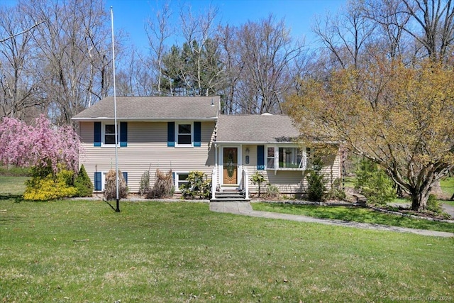split level home featuring a front yard and roof with shingles