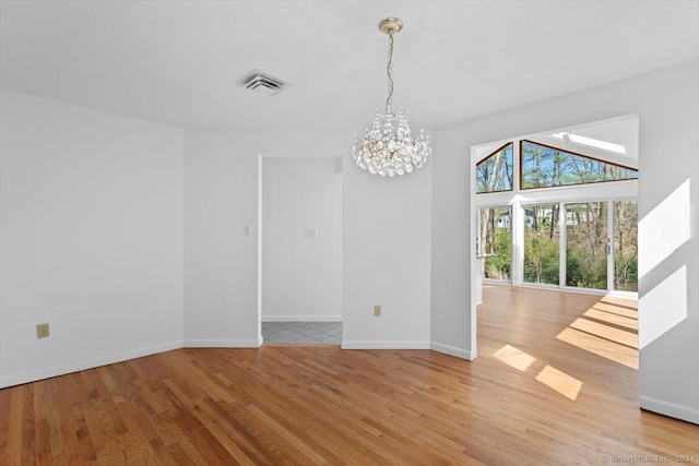 unfurnished dining area featuring light wood-style flooring, a chandelier, and baseboards