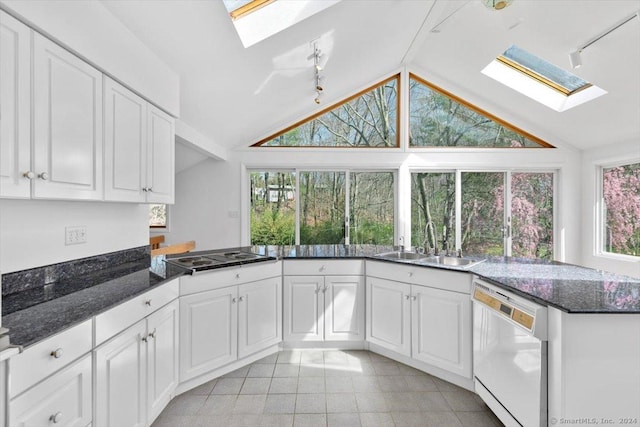 kitchen featuring a skylight, white dishwasher, a sink, electric stovetop, and lofted ceiling