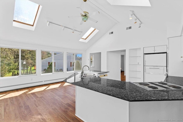 kitchen with track lighting, a skylight, a sink, freestanding refrigerator, and high vaulted ceiling