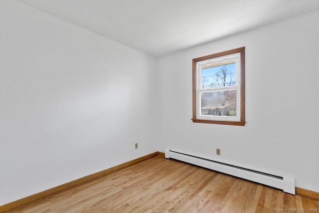 unfurnished room featuring a baseboard radiator, light wood-type flooring, and baseboards