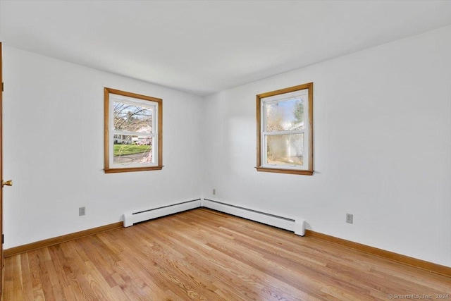unfurnished room with a baseboard radiator, light wood finished floors, and baseboards
