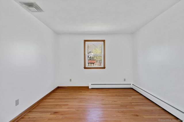 unfurnished room with a baseboard radiator, baseboard heating, light wood-style floors, and baseboards