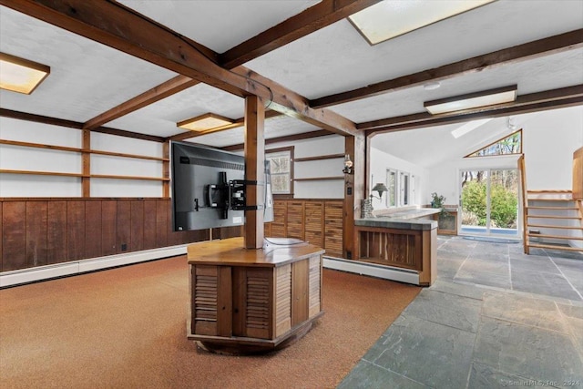 interior space with a baseboard heating unit, wooden walls, wainscoting, stone finish floors, and carpet