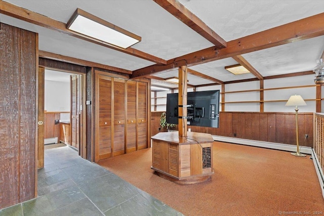 unfurnished office with wooden walls, a baseboard radiator, wainscoting, and beam ceiling