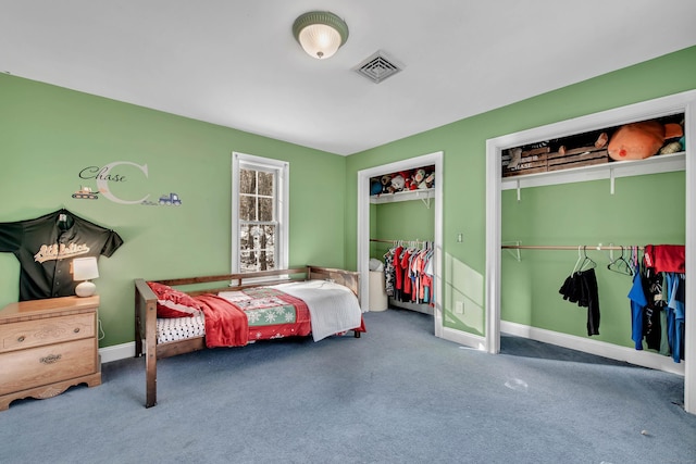 bedroom with two closets, carpet floors, and baseboards