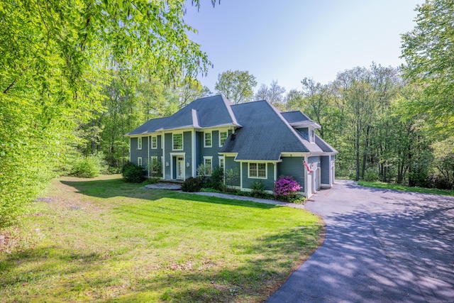 view of front of home featuring asphalt driveway, a front yard, and a garage
