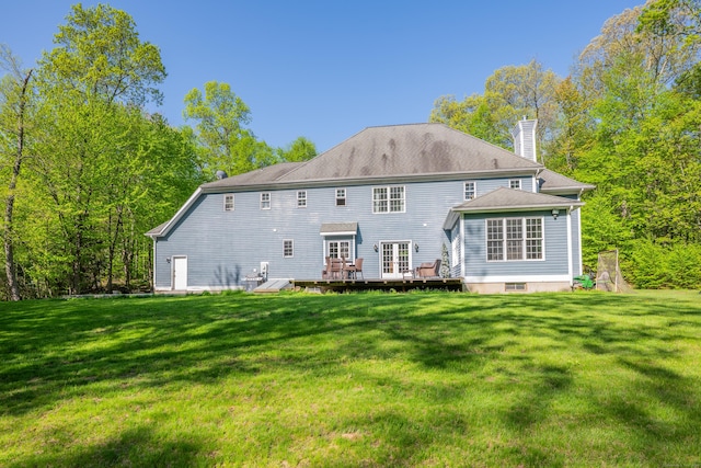 back of house featuring a wooden deck, a chimney, and a lawn
