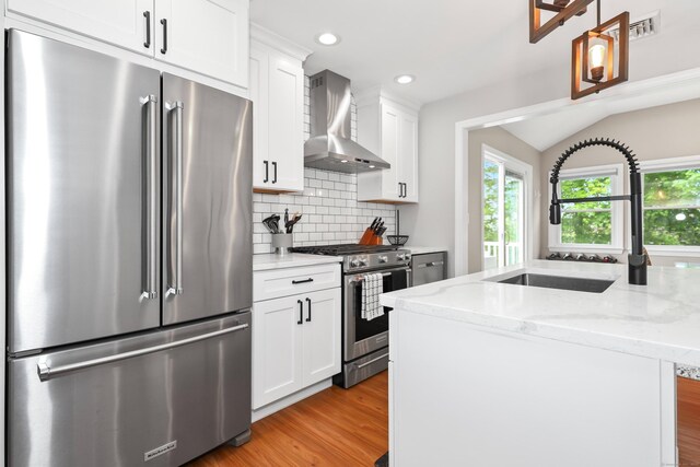 48 Sprucedale Dr, Waterbury, CT 06706 - kitchen featuring appliances with stainless steel finishes, wall chimney exhaust hood, backsplash, light wood-style flooring, and white cabinets