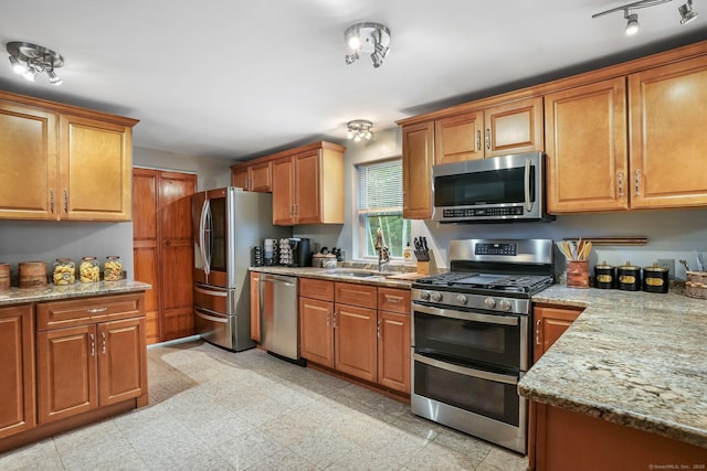 387 New London Tpke, Stonington, CT 06378 - kitchen featuring appliances with stainless steel finishes, a sink, light stone counters, and brown cabinetry