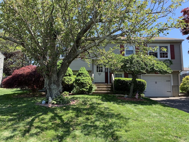 view of front of property featuring an attached garage, a front lawn, and asphalt driveway