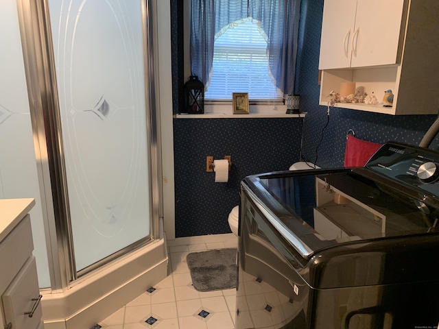 clothes washing area with washer / dryer, tile patterned flooring, and wallpapered walls