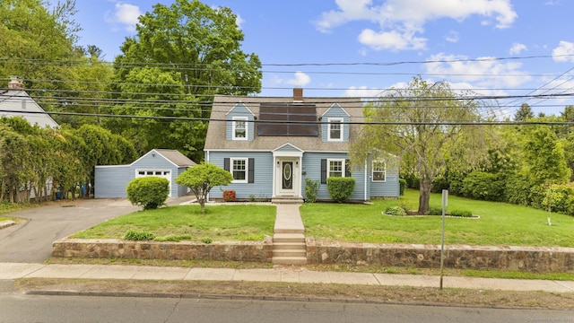 view of front facade featuring a front lawn, an outdoor structure, a shingled roof, and a garage