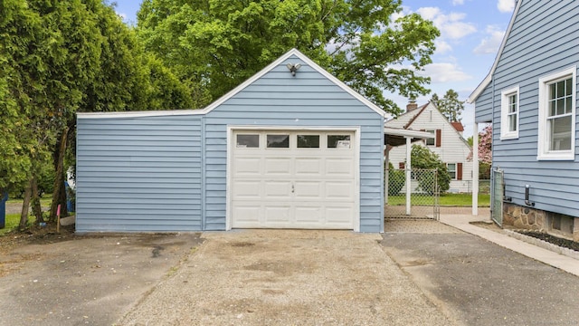 detached garage featuring driveway and fence