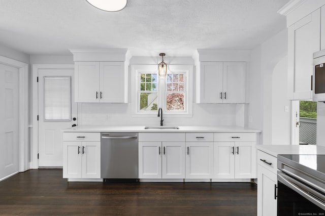 kitchen featuring a sink, stainless steel appliances, white cabinetry, dark wood finished floors, and light countertops
