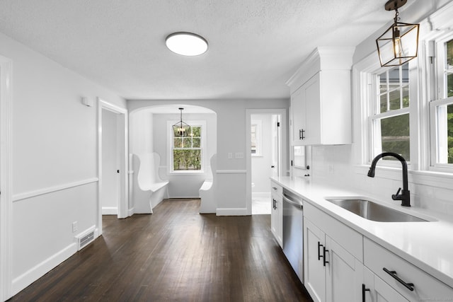 kitchen with a sink, stainless steel dishwasher, dark wood-style flooring, light countertops, and a textured ceiling