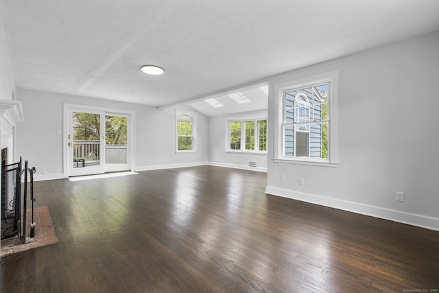 unfurnished living room with plenty of natural light, dark wood-style floors, baseboards, vaulted ceiling, and a fireplace