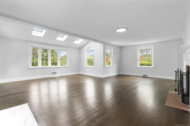 unfurnished living room featuring a fireplace with flush hearth, a skylight, dark wood finished floors, baseboards, and lofted ceiling