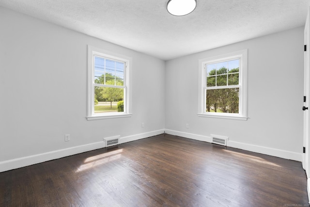 unfurnished room featuring plenty of natural light, dark wood-style floors, baseboards, and a textured ceiling