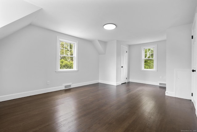 additional living space featuring dark wood finished floors, lofted ceiling, and baseboards