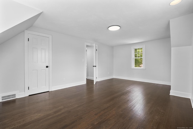 additional living space with dark wood finished floors and baseboards
